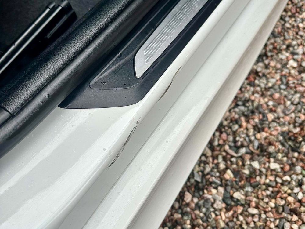 Repor och märken i den vita lacken vid tröskeln på en BMW före punktpolering